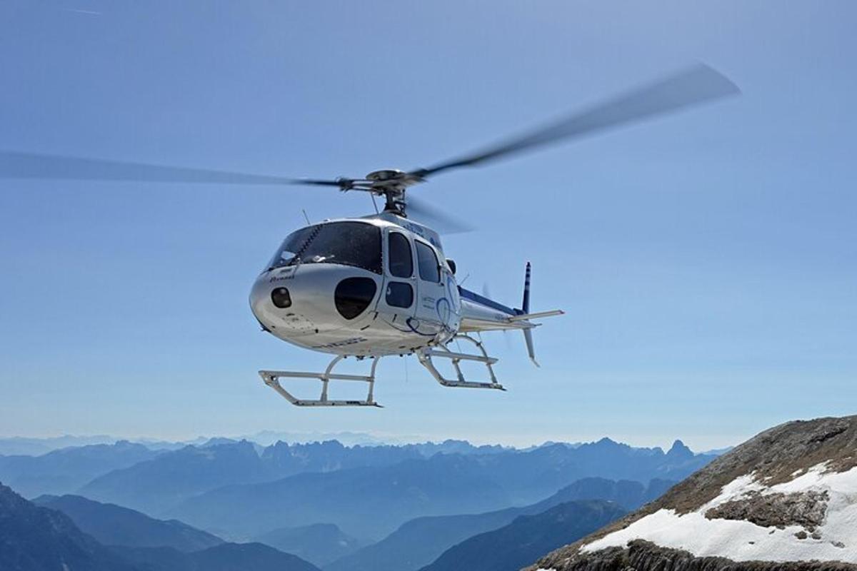 Helikopter leti nad zasneženo goro