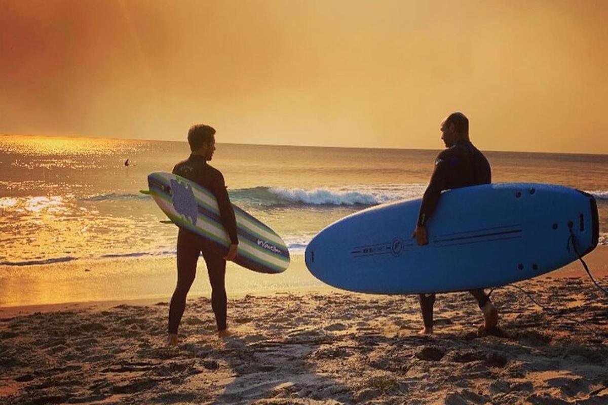 doi bărbați stând pe plajă cu plăcile lor de surf
