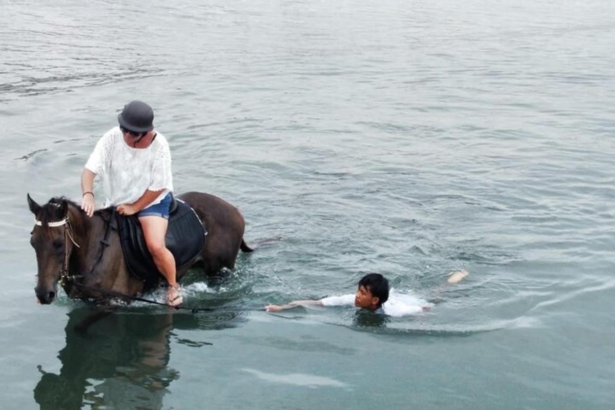 Un hombre montado a caballo y un niño en el agua.