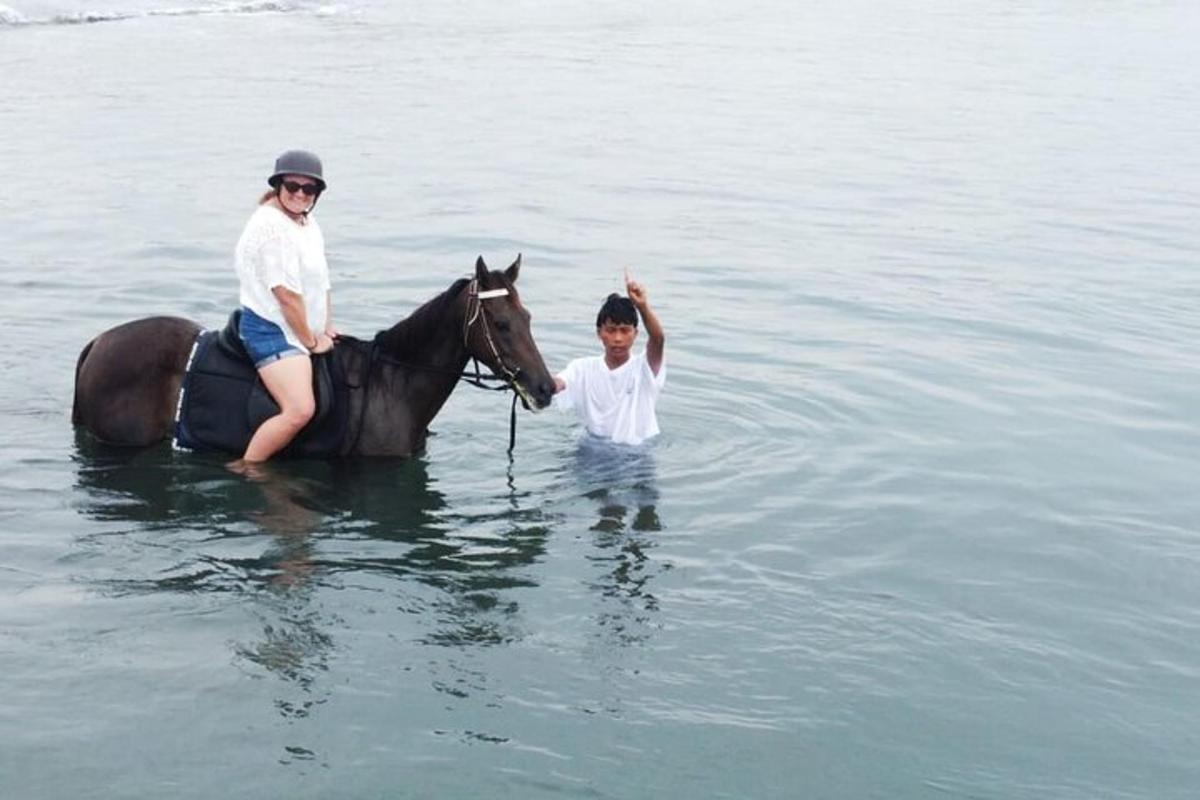 Una mujer y un niño montando a caballo en el agua