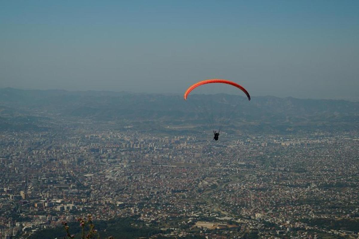 a person in a parachute flying over a city