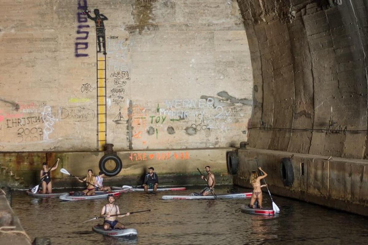 un gruppo di persone che fa kayak nell'acqua sotto un ponte