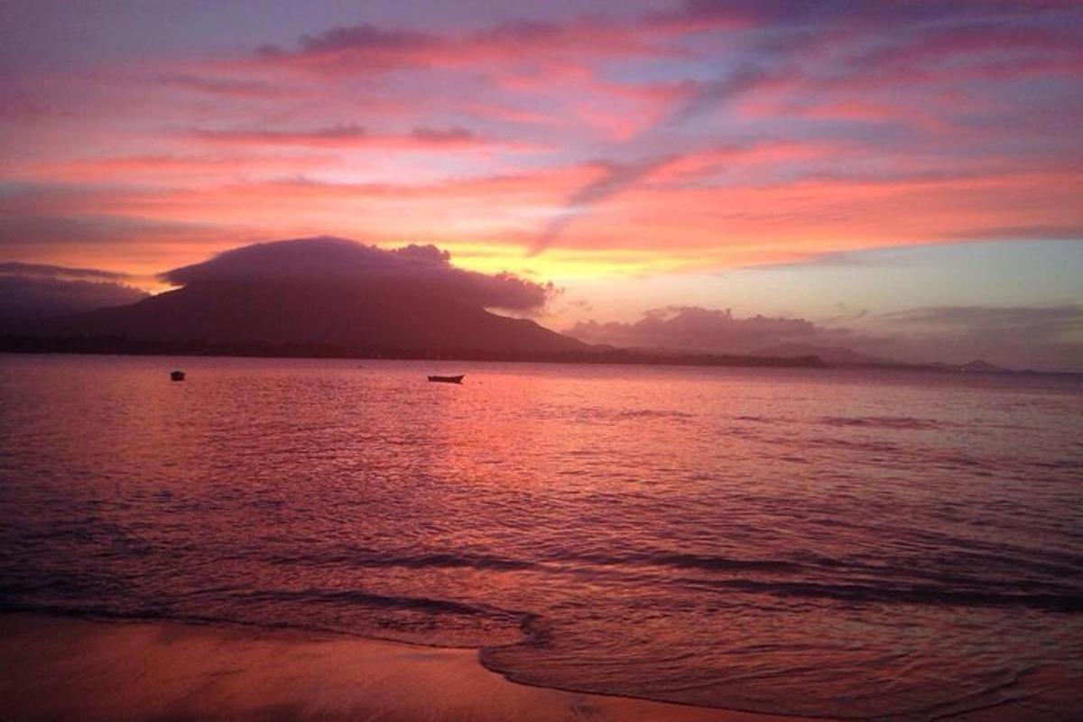 a sunset on the beach with a boat in the water