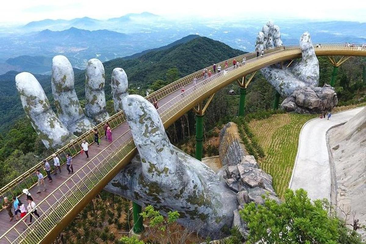 una statua di mani che sorreggono un ponte sopra una montagna