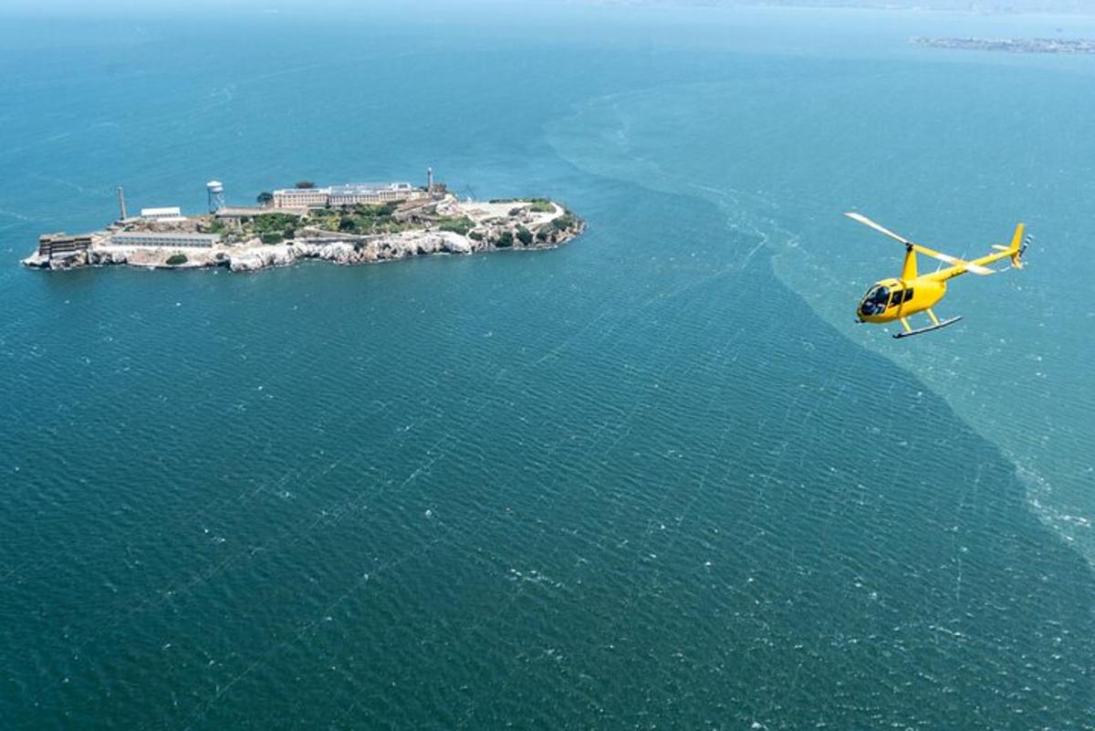 sebuah helikopter kuning terbang di atas sebuah pulau di lautan