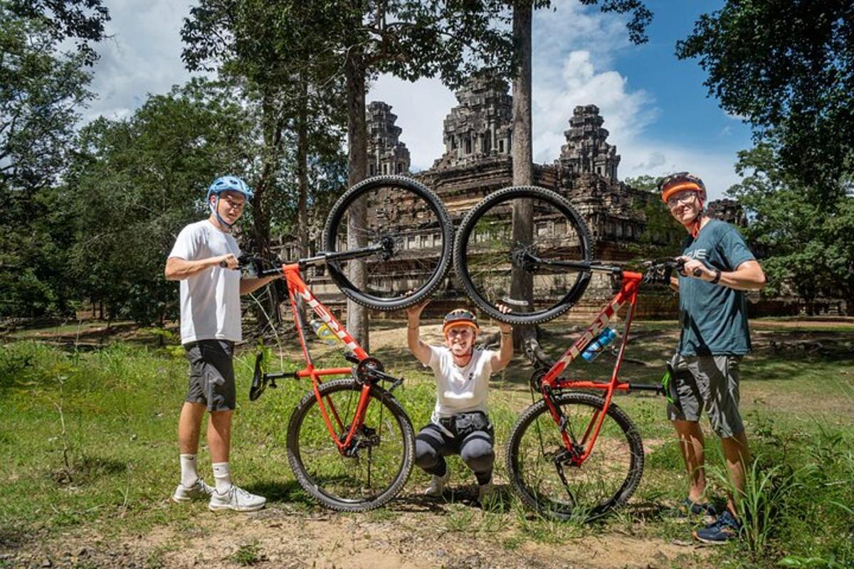 a group of three people holding up their bikes