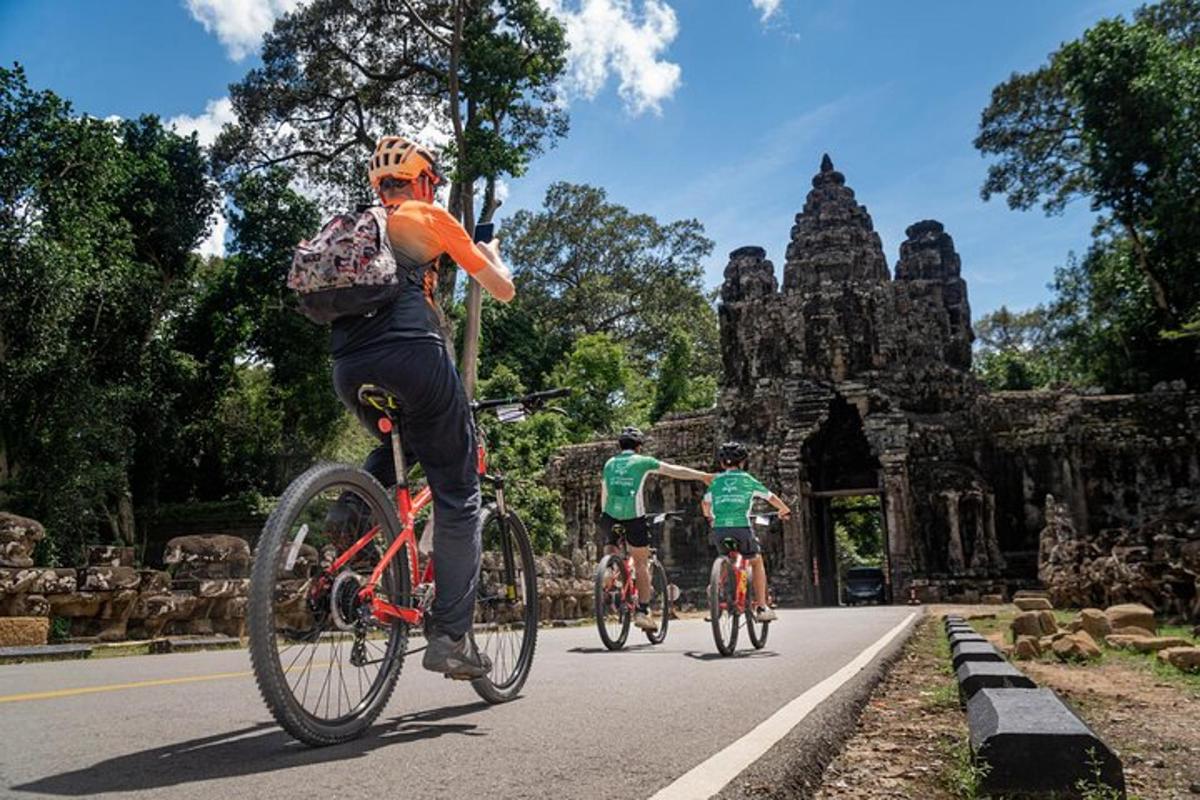 tiga orang mengendarai sepeda di jalan di depan sebuah gedung