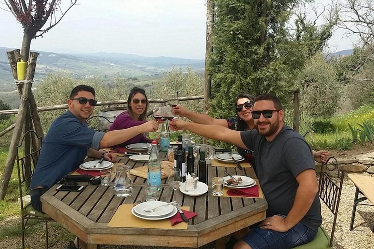 cilvēku grupa sēž pie galda un dzer vīnu