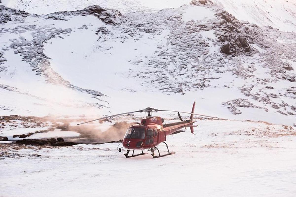 un elicopter parcat în zăpadă lângă un munte