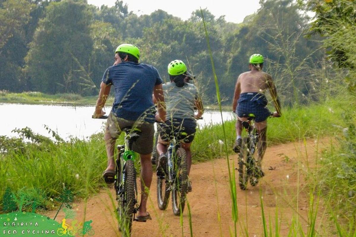 tatlong tao na nagbibisikleta sa isang dumi na trail malapit sa isang ilog