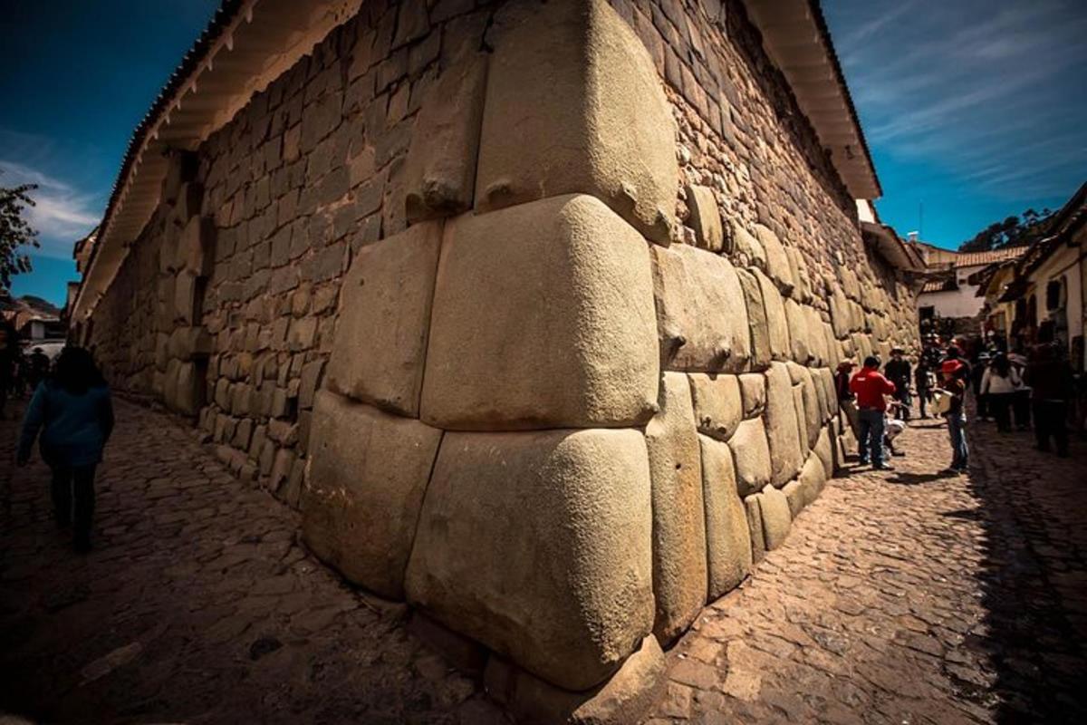 a group of people walking down a street next to a stone wall