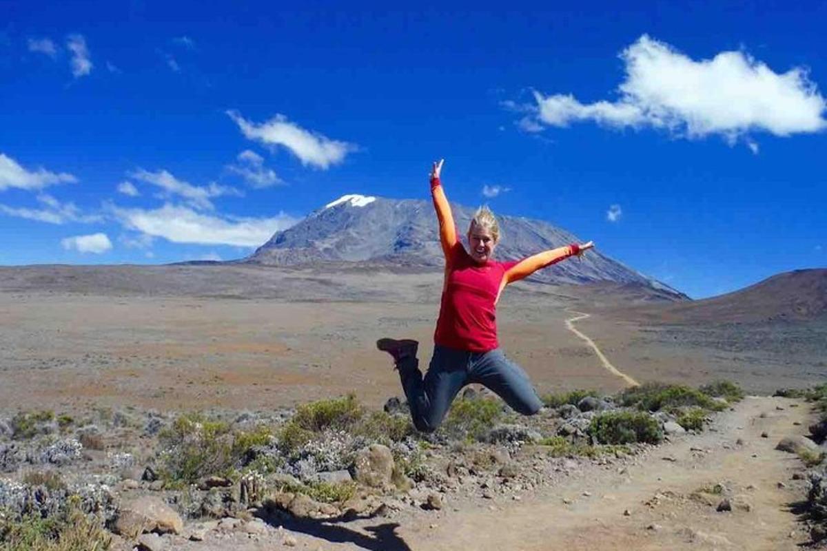 seorang wanita melompat di udara di hadapan gunung