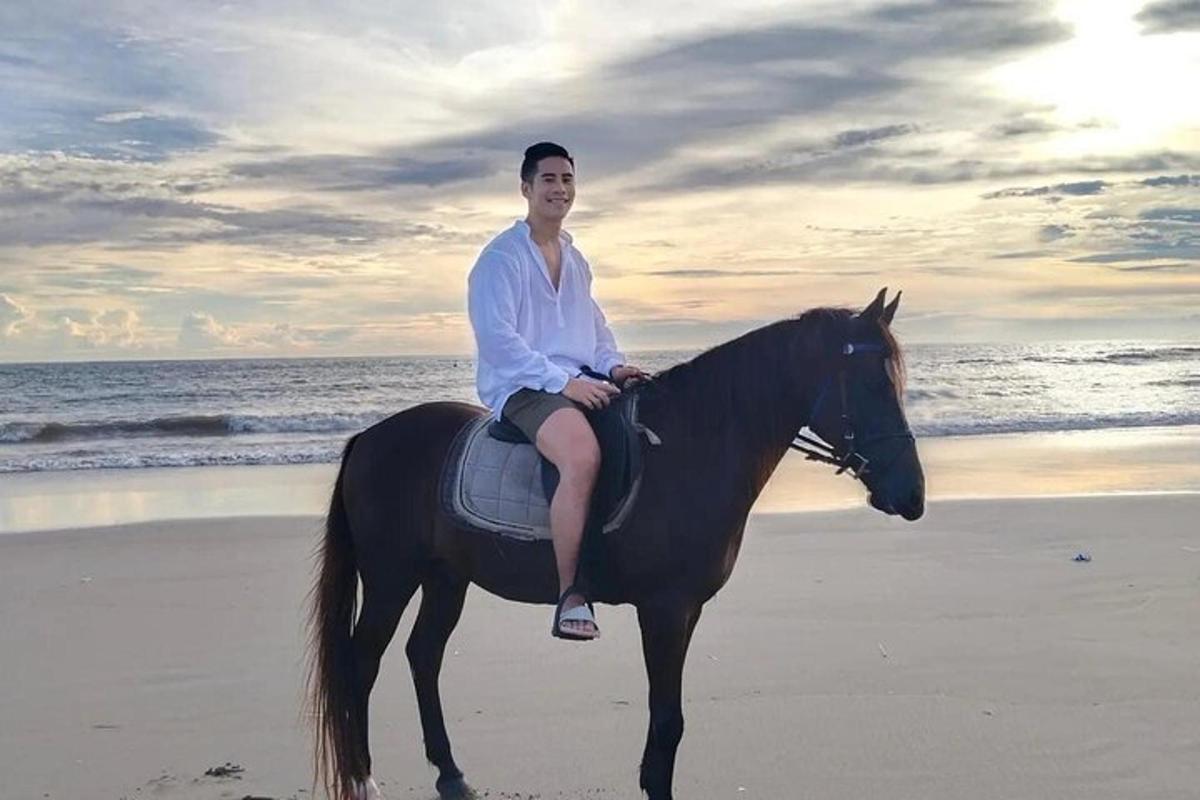 un home assegut a cavall a la platja