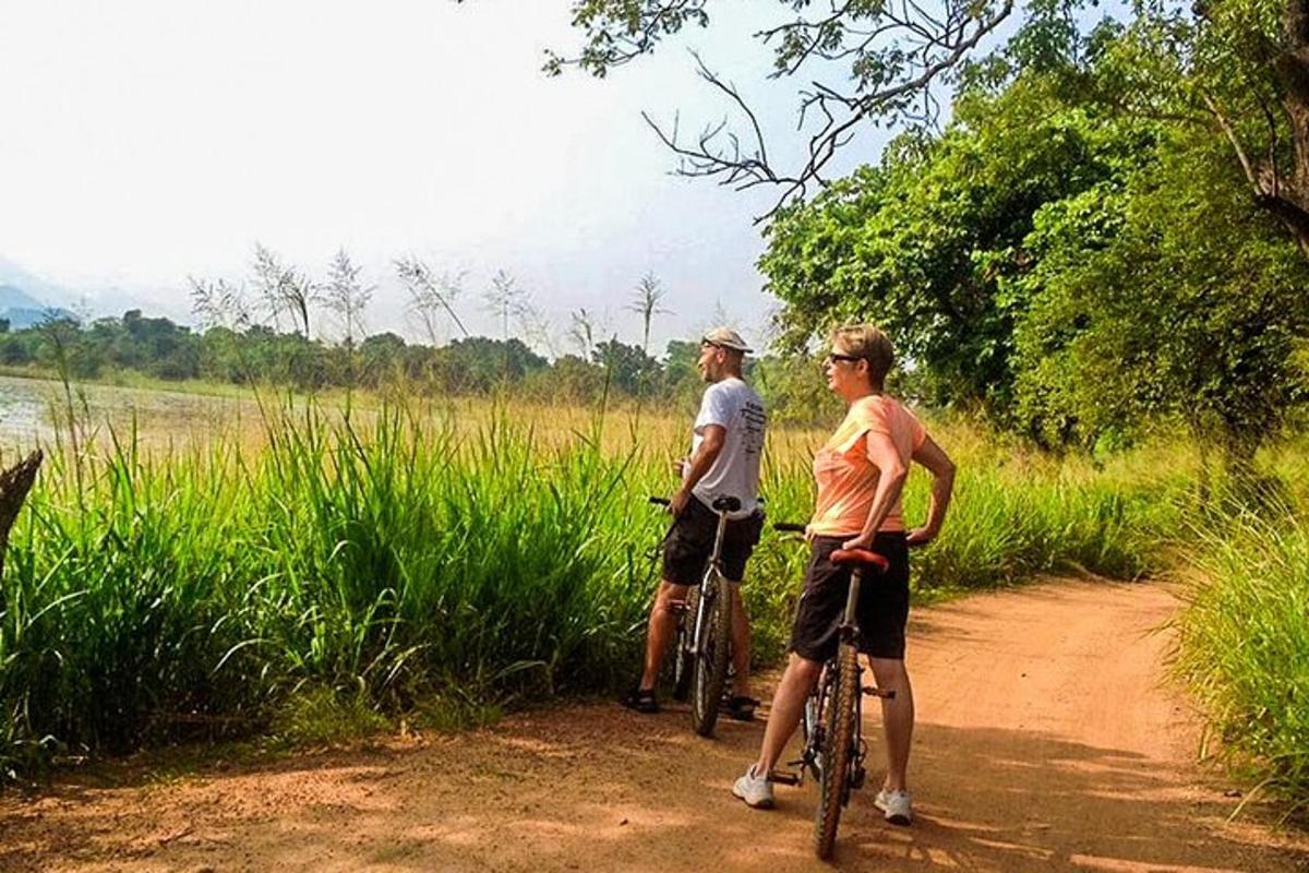 two people riding bikes on a dirt road
