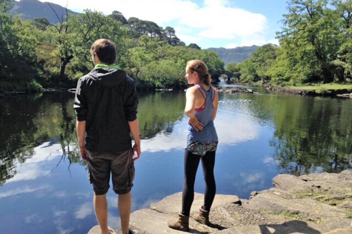 a man and a woman standing on rocks near a river