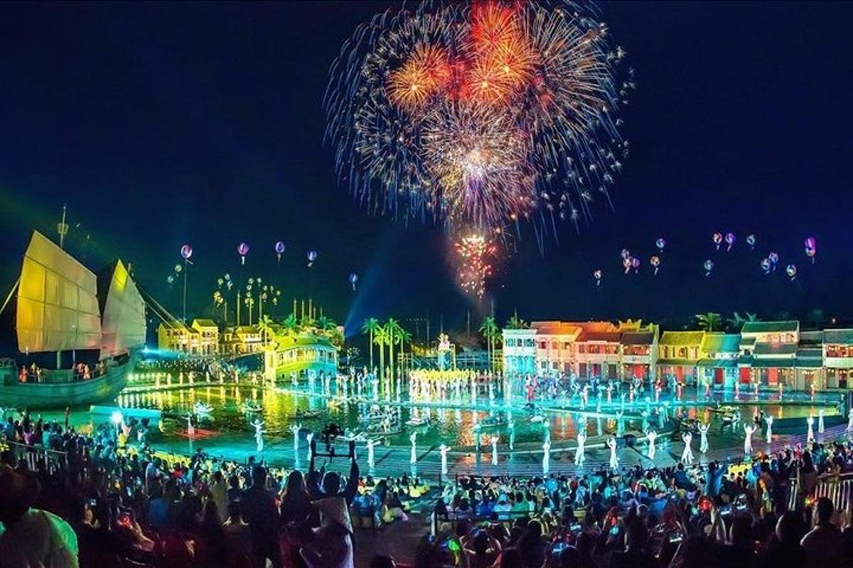 Mannfjöldi stendur fyrir framan gosbrunn með flugeldum