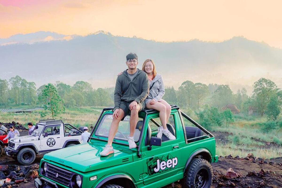 un uomo e una donna seduti sul cofano di una jeep verde