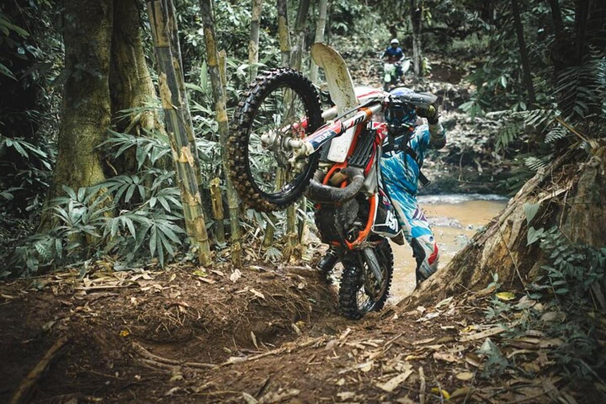 una persona fent un truc amb una moto de cross al bosc