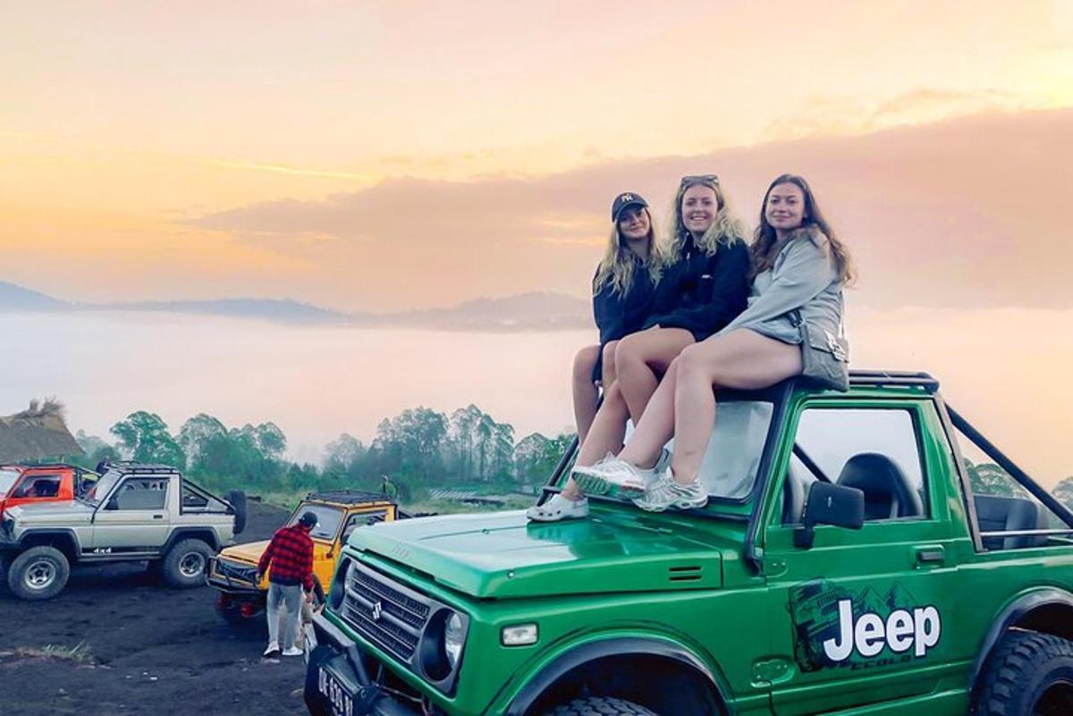 drei Mädchen sitzen auf dem Dach eines grünen Jeeps