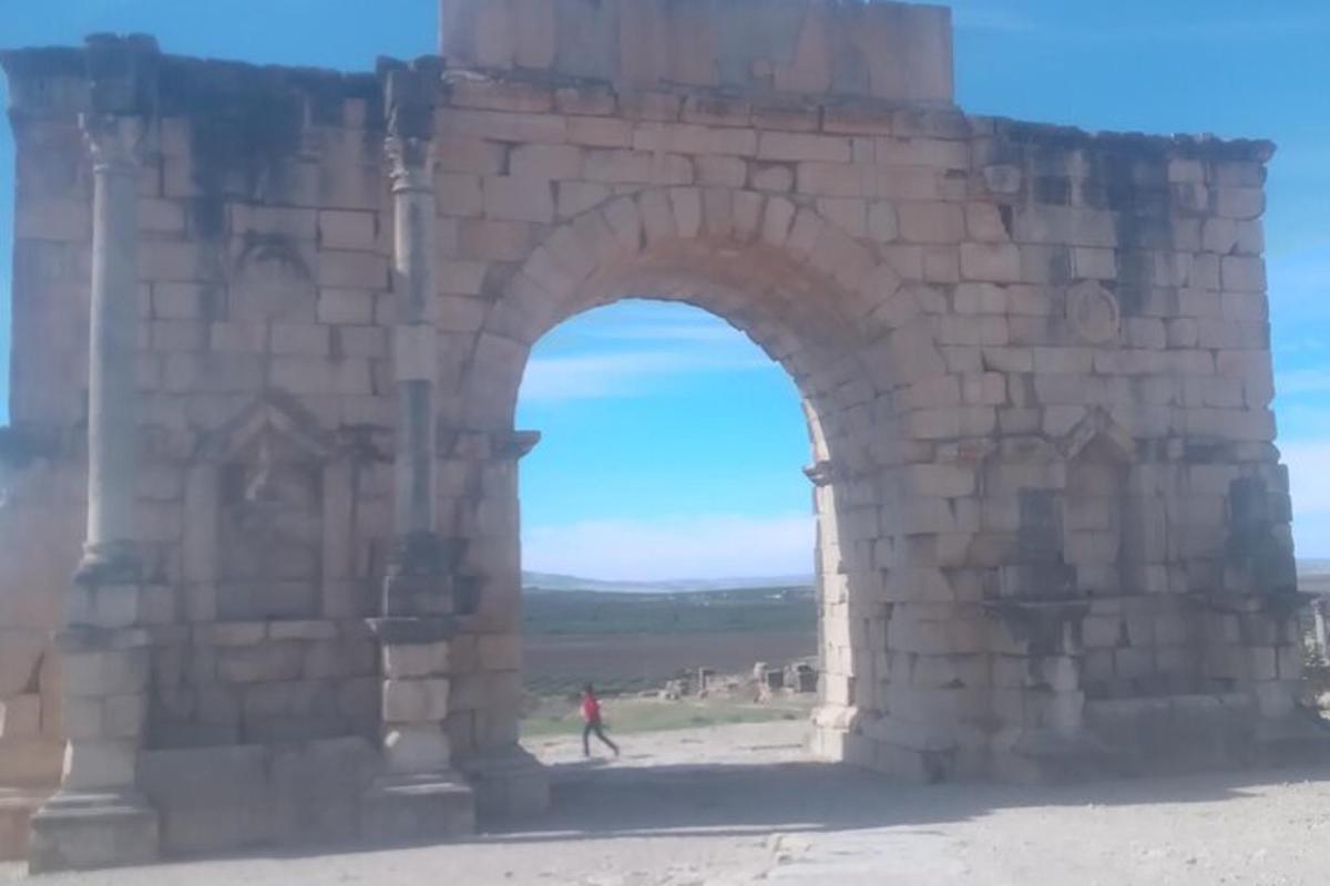 oblouk v kamenné budově s osobou kráčející pod ním