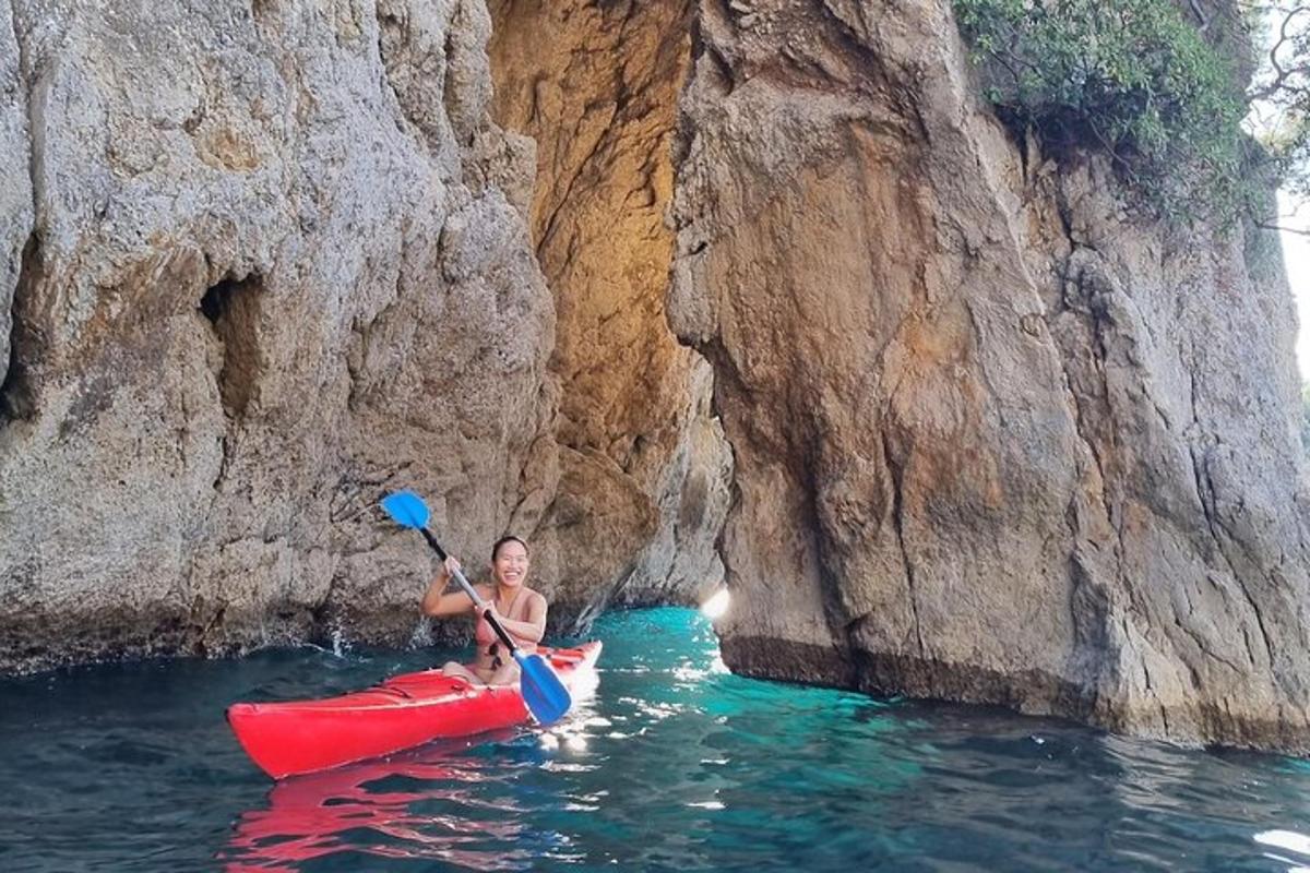 una donna in kayak in acqua accanto a una scogliera