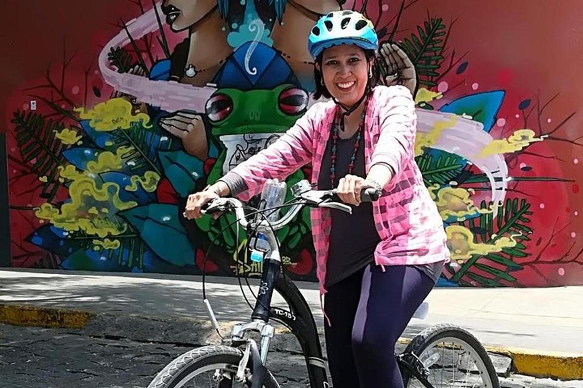 o femeie mergând pe bicicletă în fața unei picturi murale
