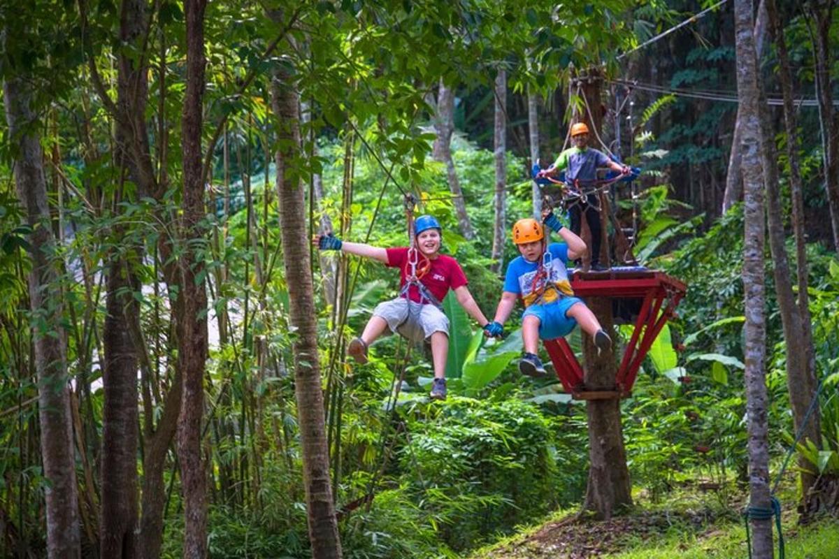 tři lidé jedoucí na zip line v lese