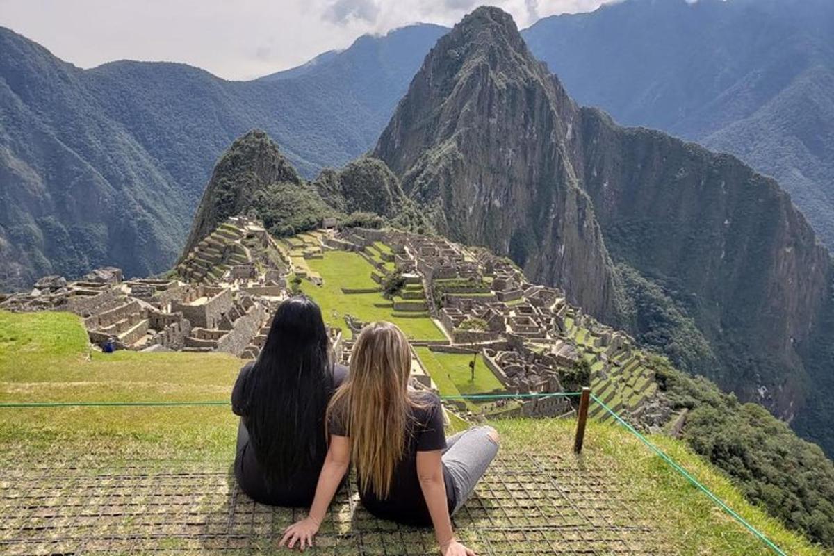 Dos mujeres sentadas en una cornisa mirando las ruinas de una montaña
