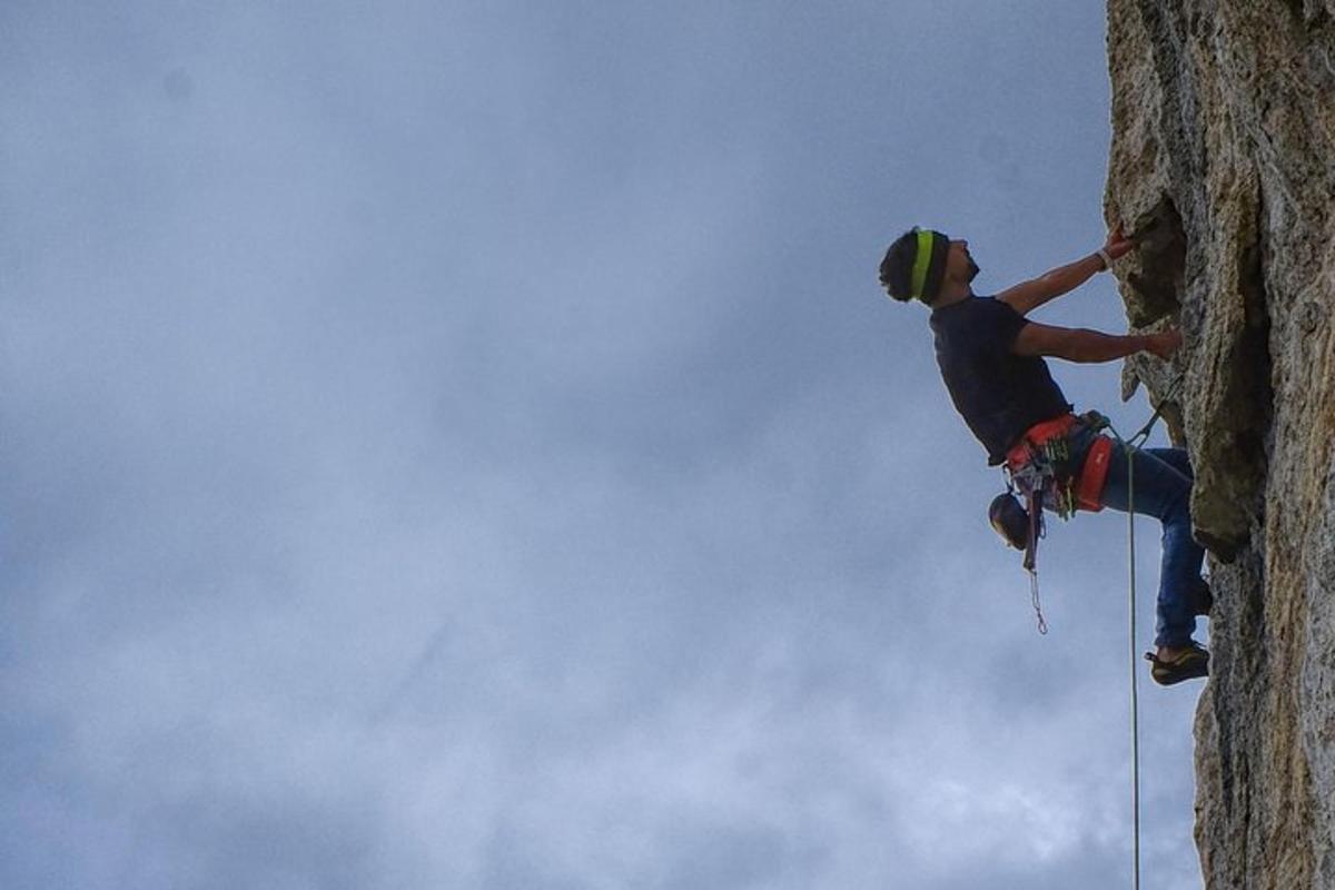 un uomo si sta calando in corda doppia da una parete rocciosa