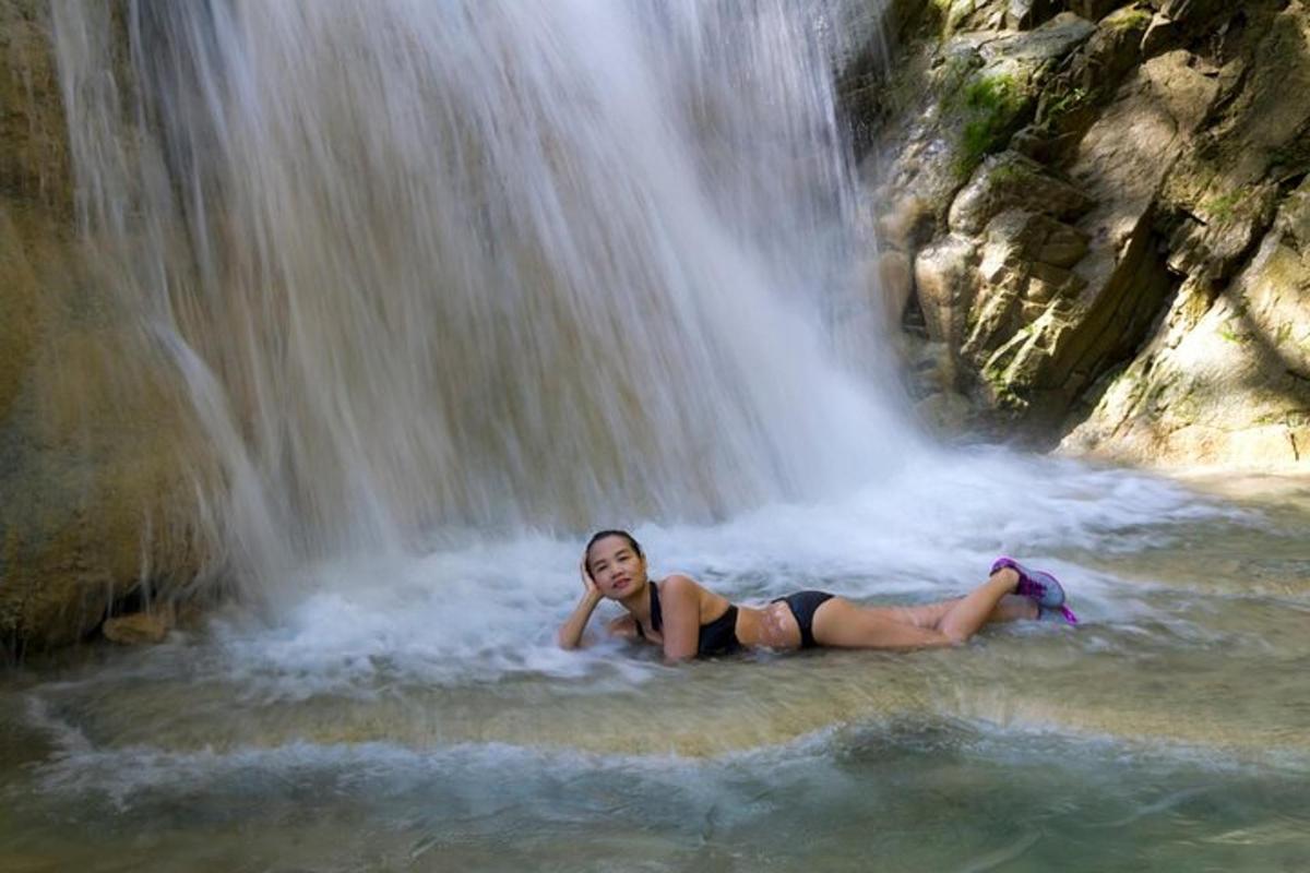 žena ležící ve vodě před vodopádem