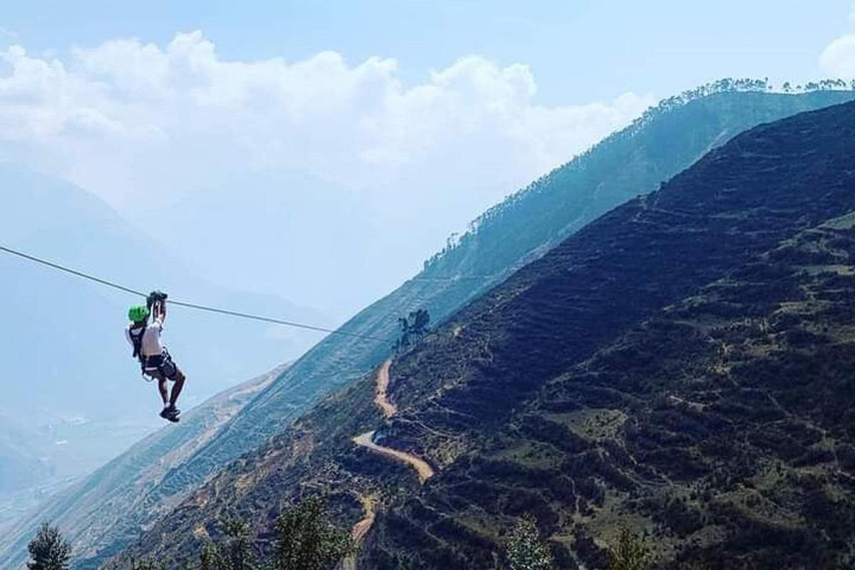 산 위의 지플라인에 있는 사람