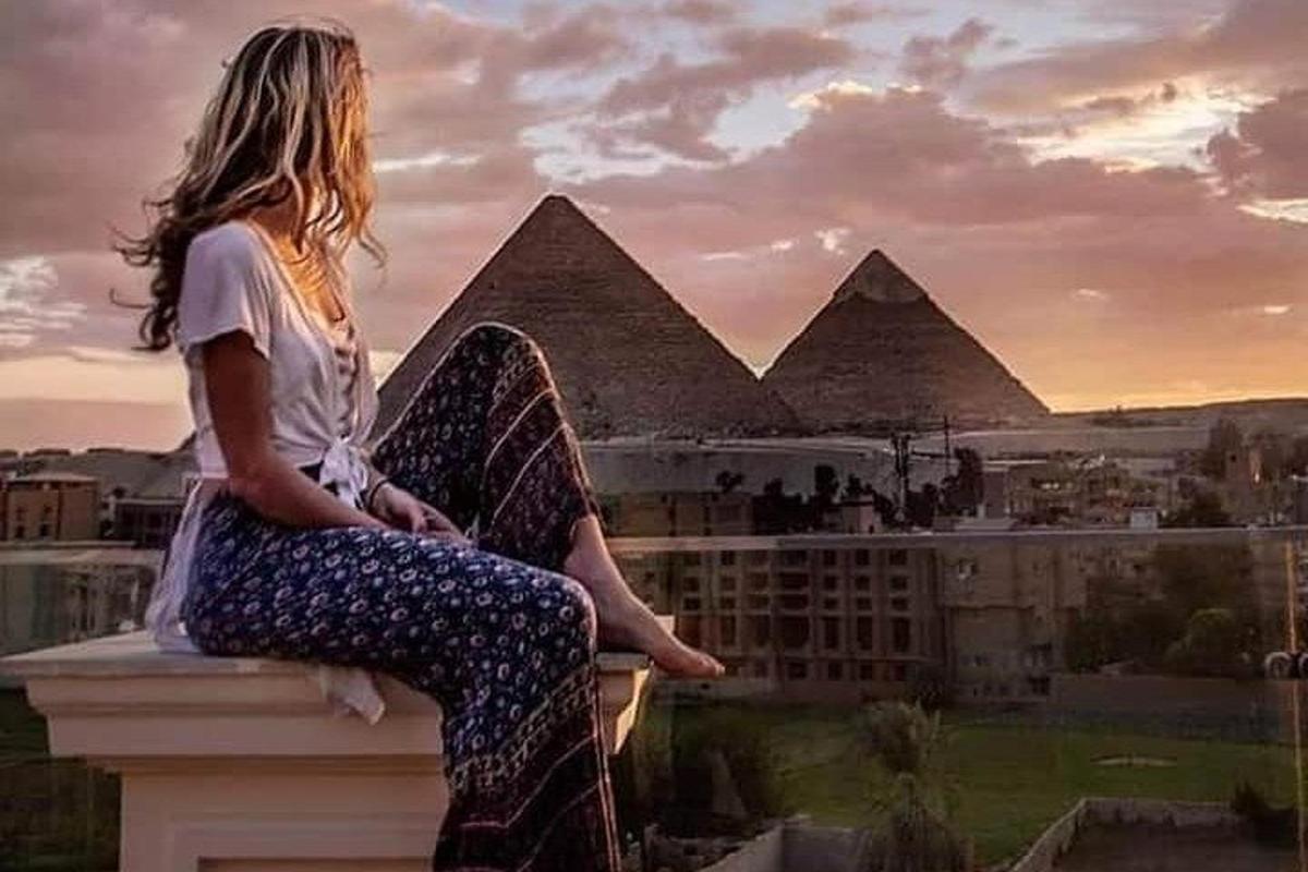 una donna seduta su una sporgenza che guarda le piramidi
