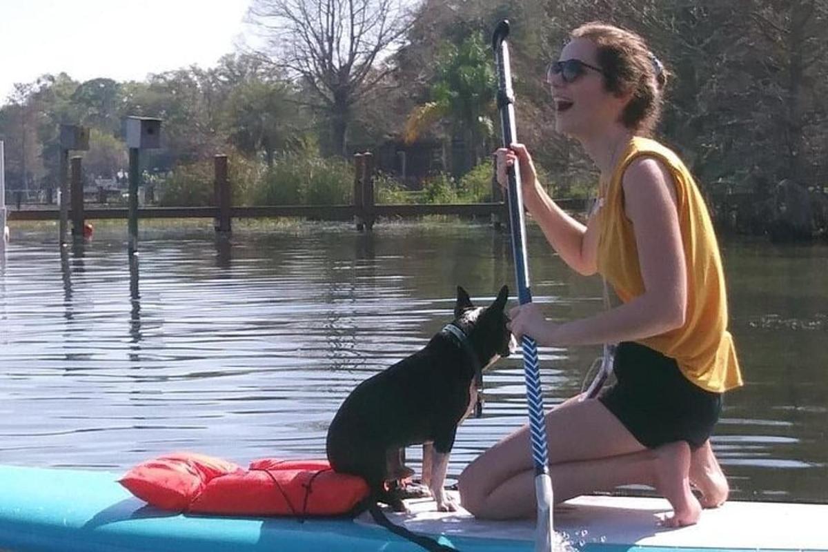 žena držící psa na paddleboardu