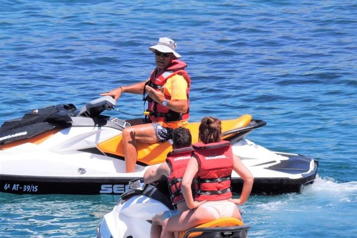un home i dues persones en una moto aquàtica a l'aigua