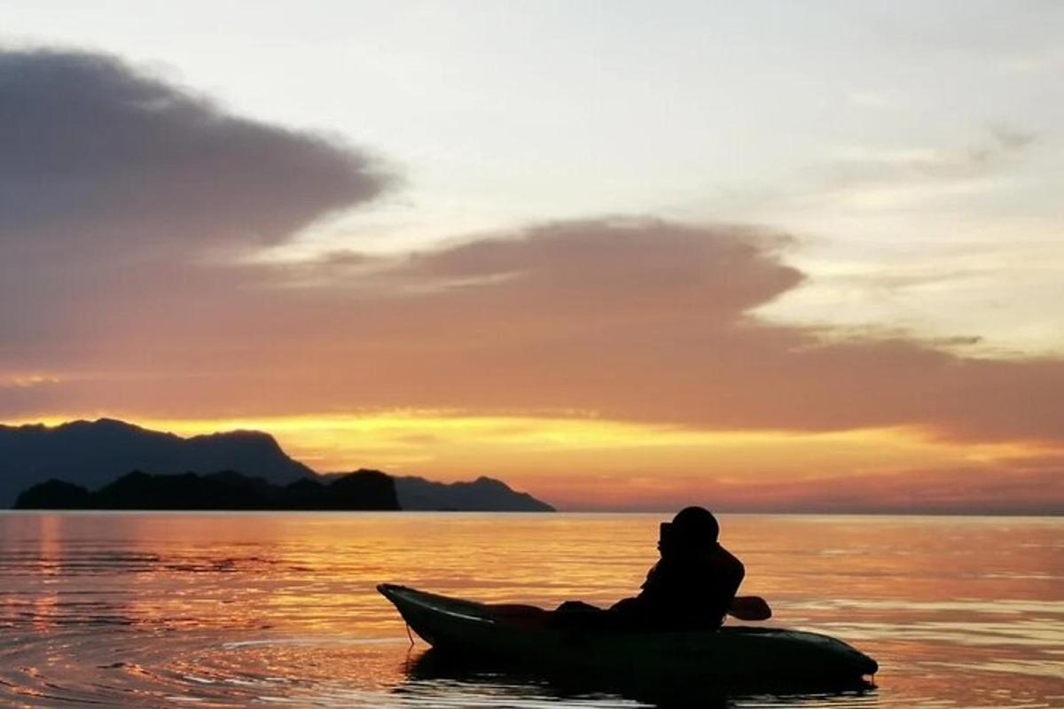 een persoon die bij zonsondergang op een kajak in het water zit
