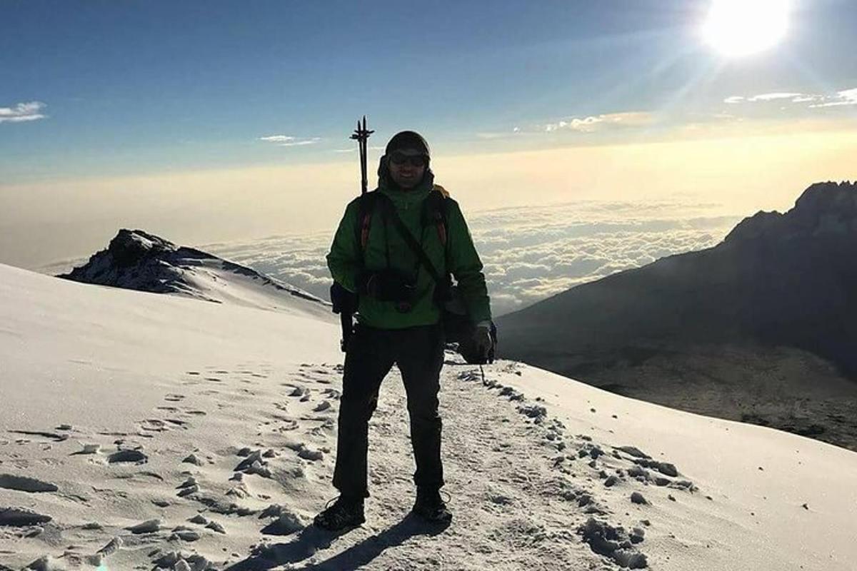 Un hombre parado en la cima de una montaña cubierta de nieve