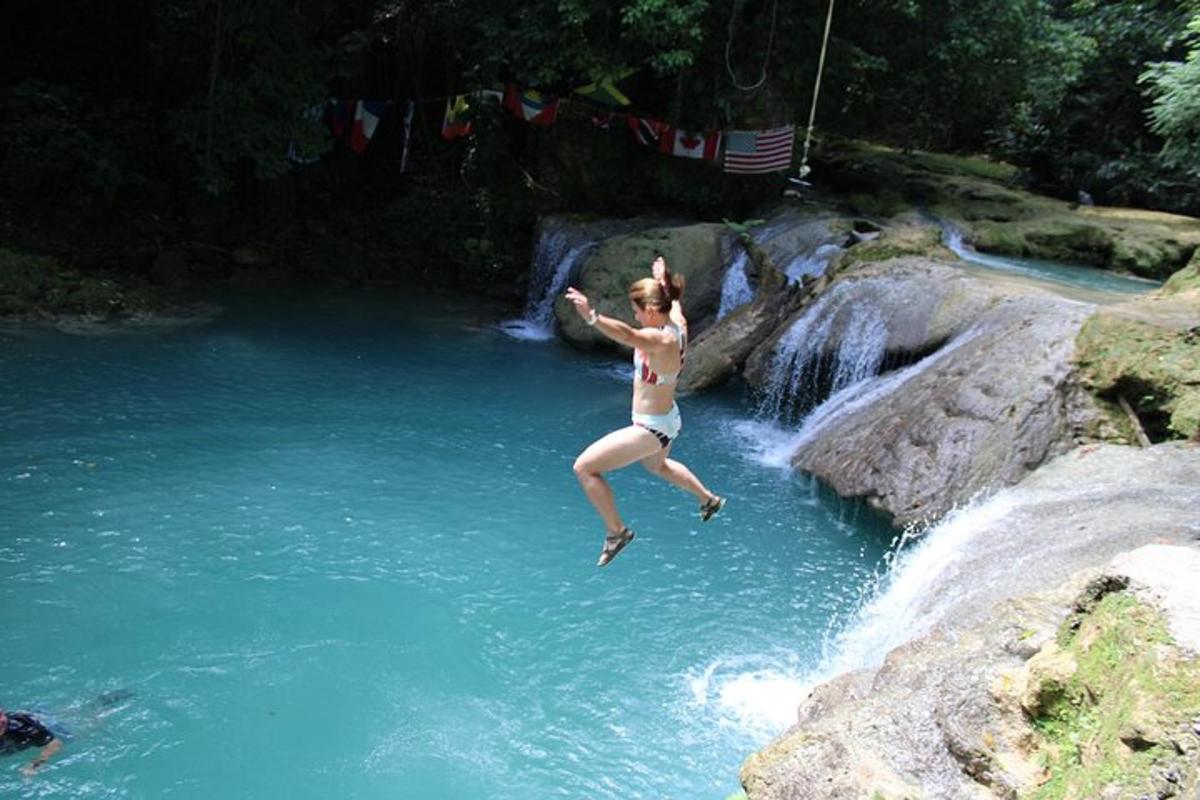 a woman jumping off a waterfall into a river