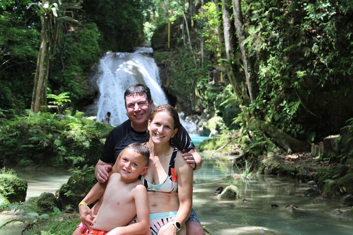 um homem, uma mulher e uma criança em frente a uma cachoeira