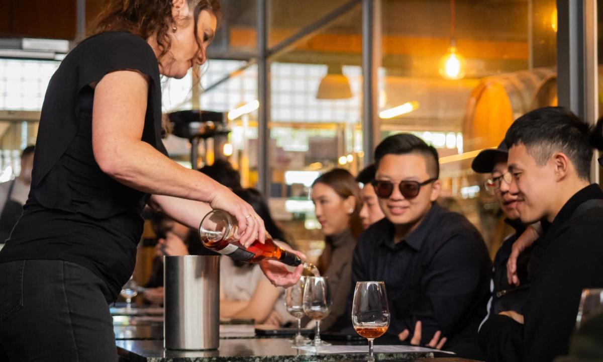 Una mujer sirviendo una copa de vino en un bar.