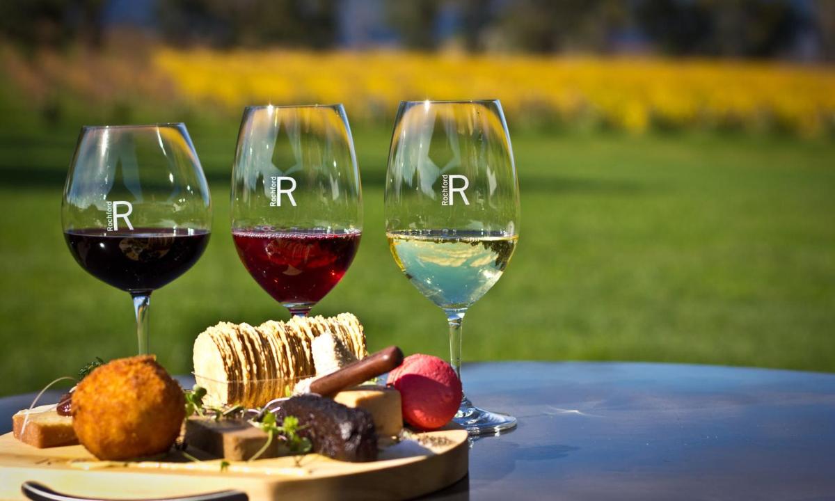 Tres copas de vino sentadas en una mesa con comida.