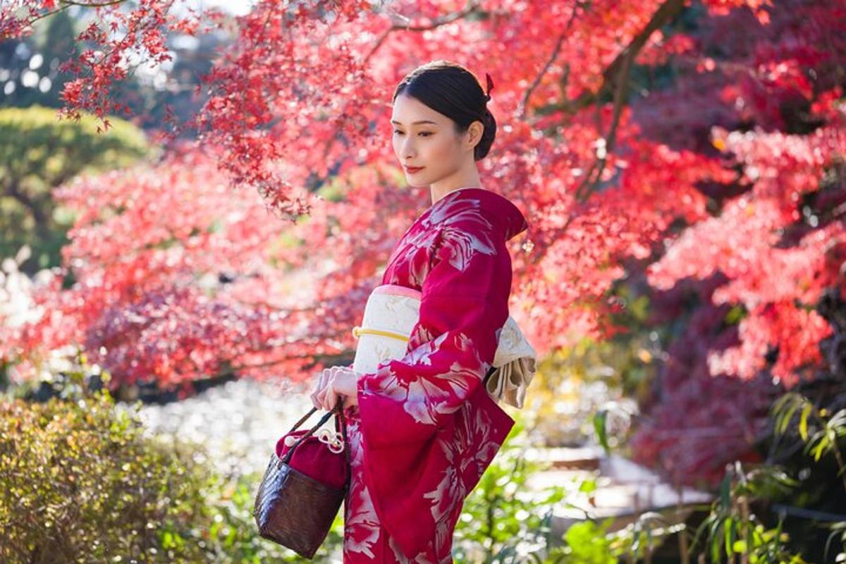 Punaiseen kimonoon pukeutunut nainen seisoo puutarhassa
