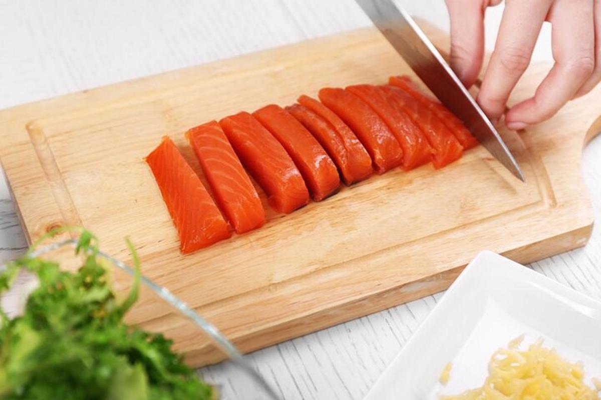 一个人用刀在砧板上切胡萝卜