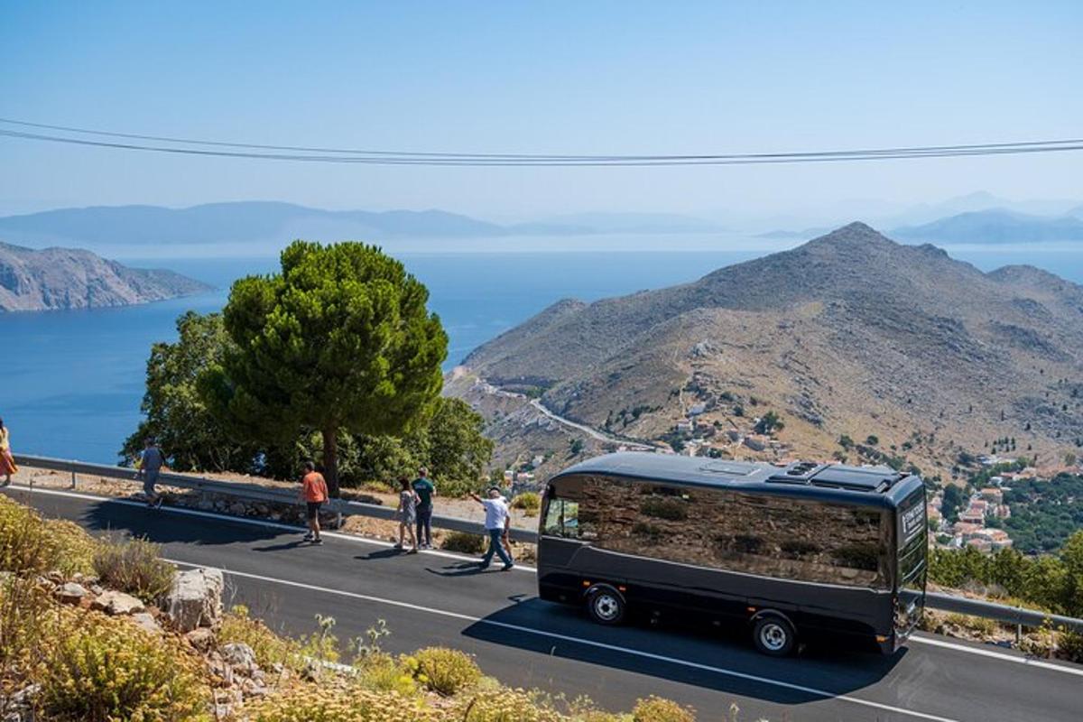 a black bus driving down a road with people walking