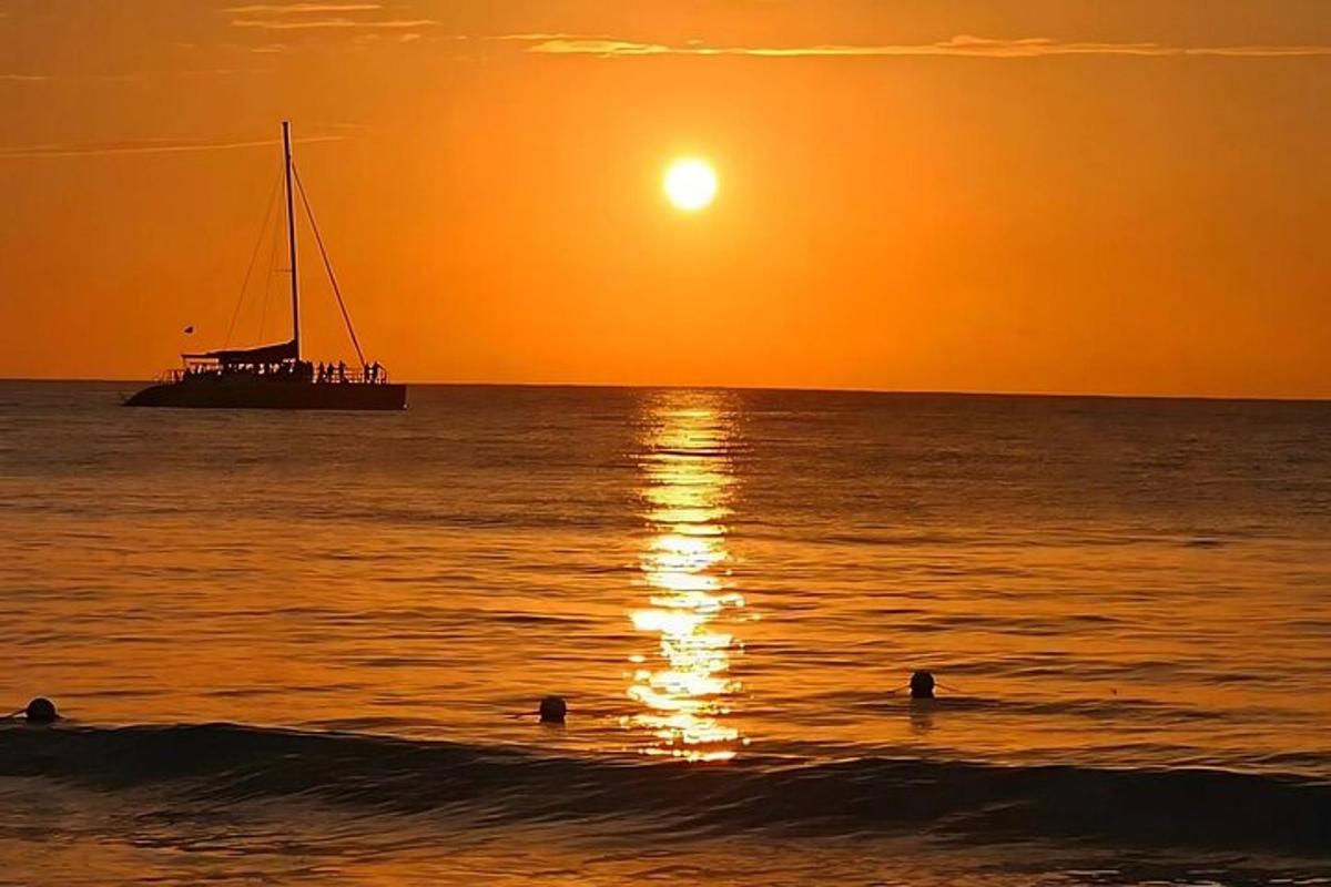 una barca nell'oceano al tramonto con persone in acqua