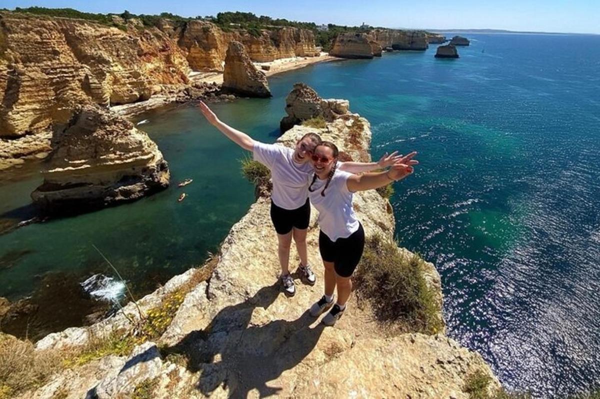 two women standing on a cliff near the ocean
