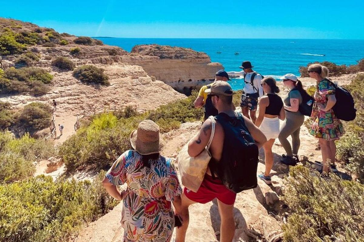 a group of people walking on a trail near the ocean
