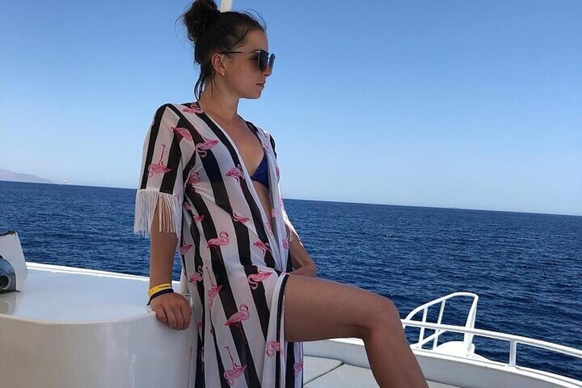 una dona amb una tovallola asseguda a la vora d'una barca