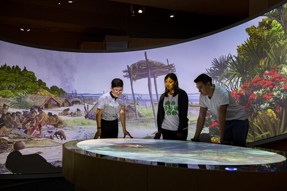 a group of people standing around a table in front of a mural
