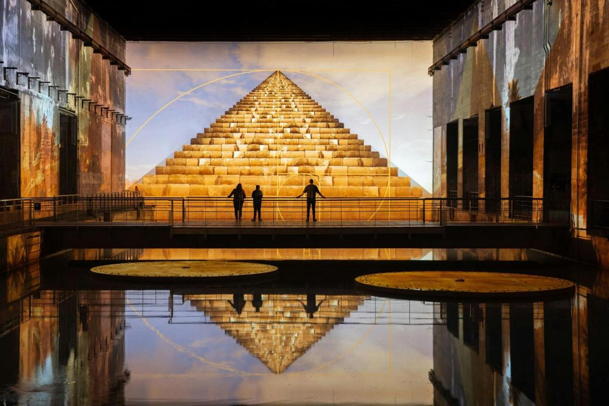 dva lidé stojící před pyramidou