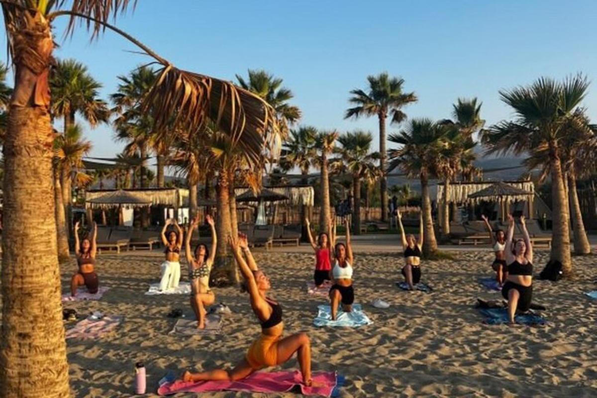 a group of people doing yoga on the beach